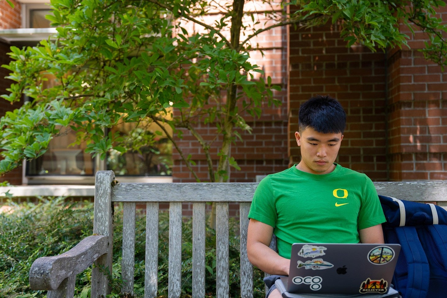 Man sitting on a bench working on a laptop