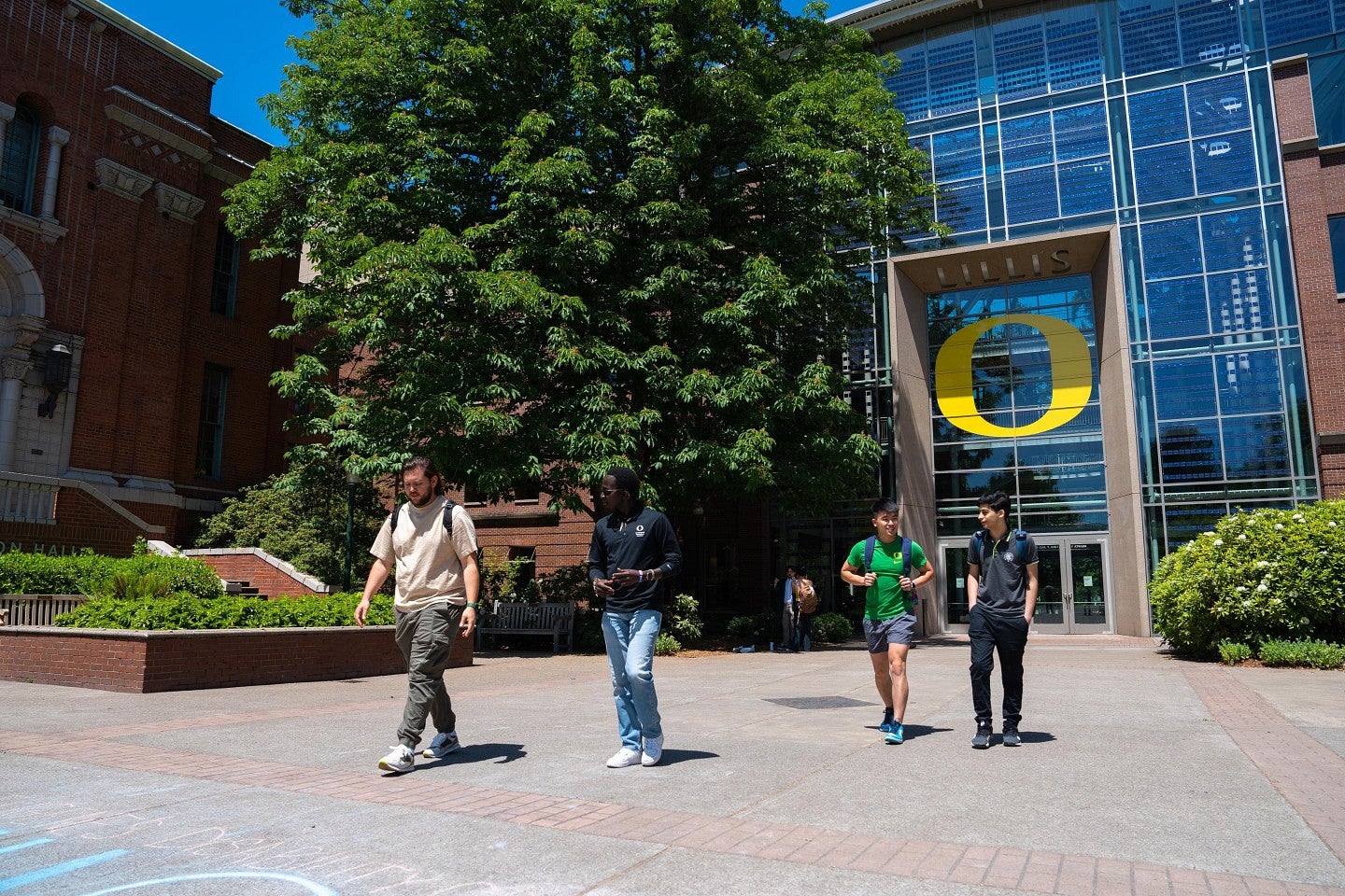 Four men walking outside of the Lillis Business Complex