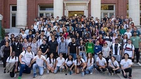 Large group of students smiling outside of the University of Oregon's Johnson Hall.