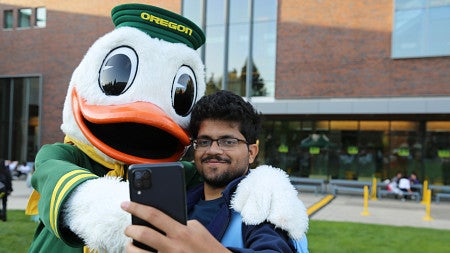 international student taking a selfie with the Oregon Duck mascot