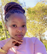 College-aged woman in a purple top posing for a selfie with her chin resting on her hand. 